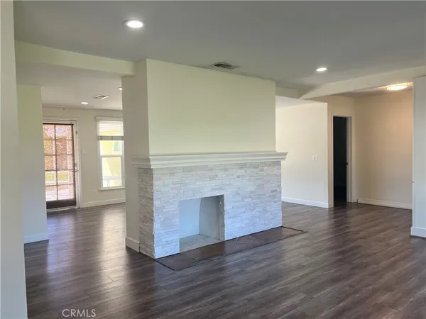 a view of an empty room with wooden floor and a fireplace