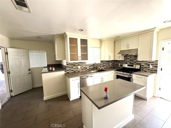 a kitchen with granite countertop a sink a stove and refrigerator