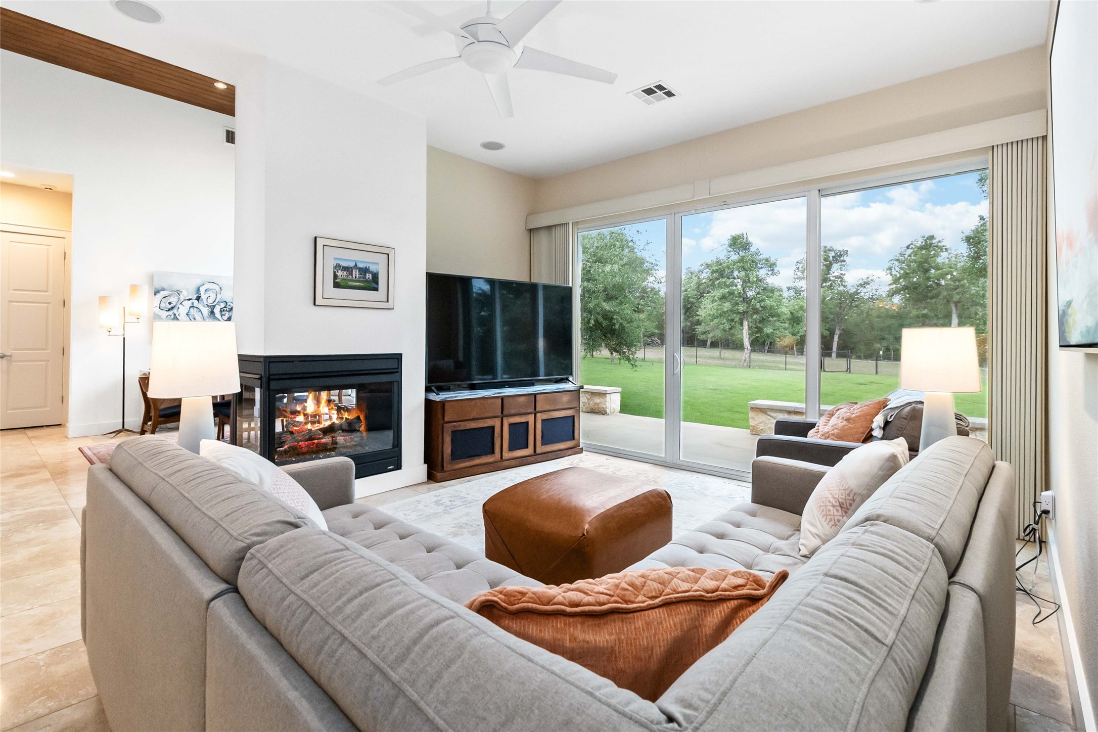 129 Powder Horn Road Bastrop, TX 78602 - Photo 8 of 27 Living area featuring a multi sided fireplace, light tile patterned flooring, and ceiling fan