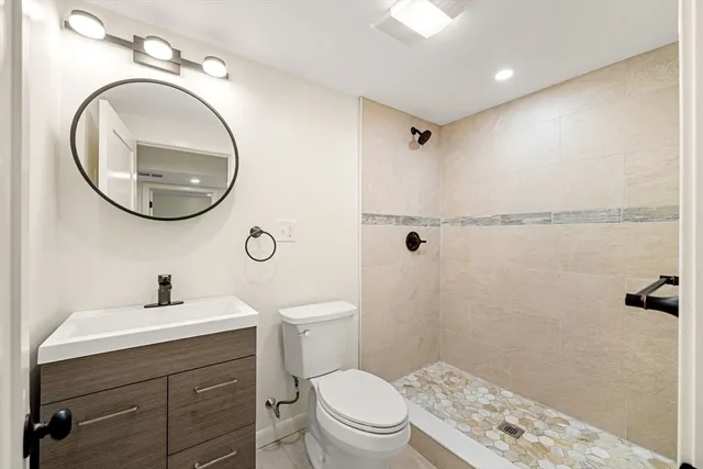 a bathroom with a toilet sink vanity and mirror