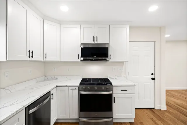 a kitchen with granite countertop white cabinets and black appliances