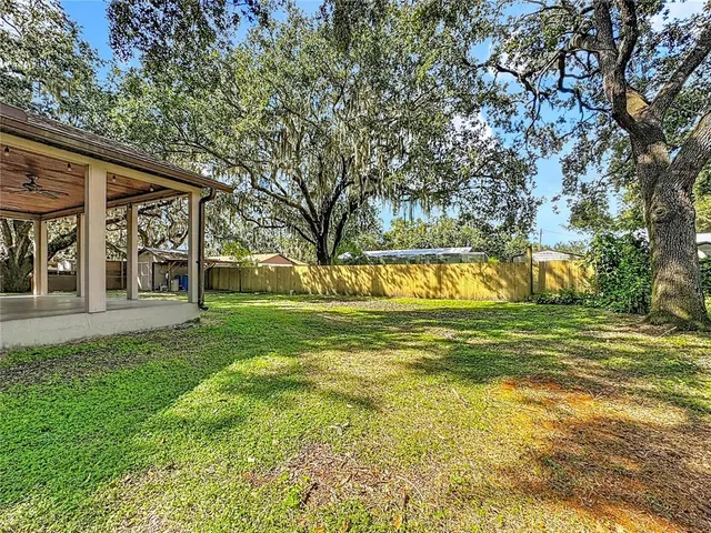 a view of a house with a big yard and large trees