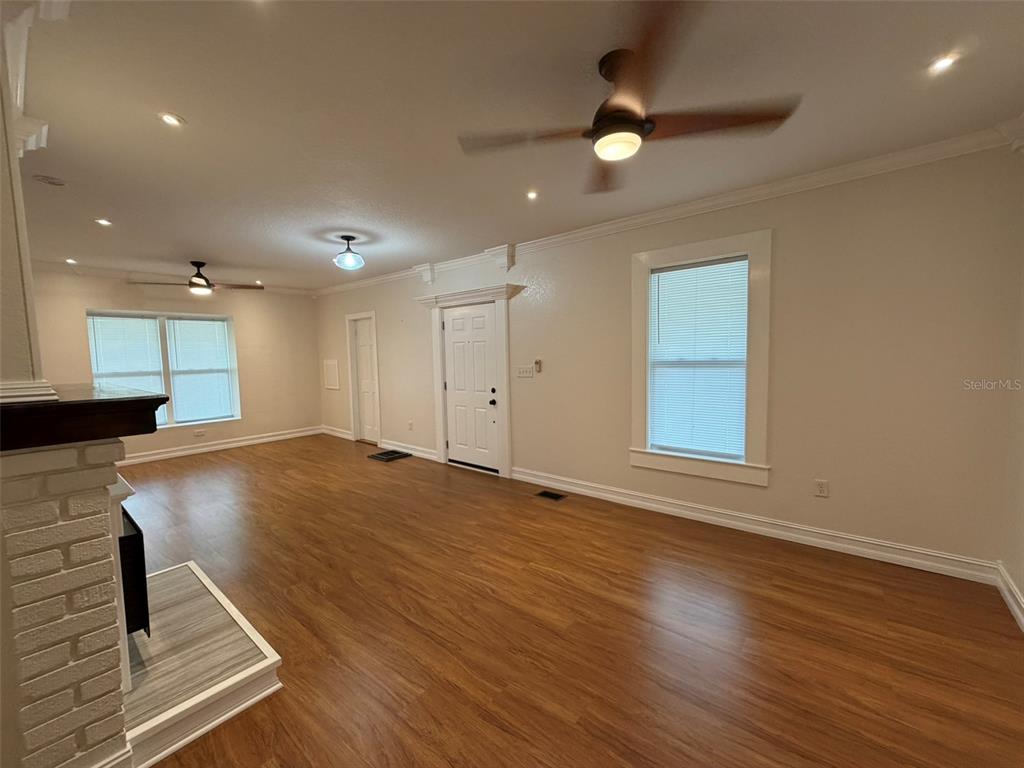 903 East New York Avenue DeLand, FL 32724 - Photo 9 of 29 an empty room with wooden floor a ceiling fan and windows