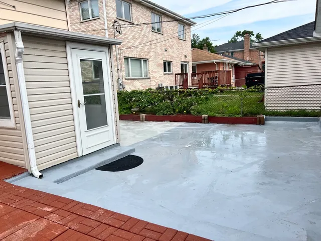 a view of a white house with a small yard plants and large tree