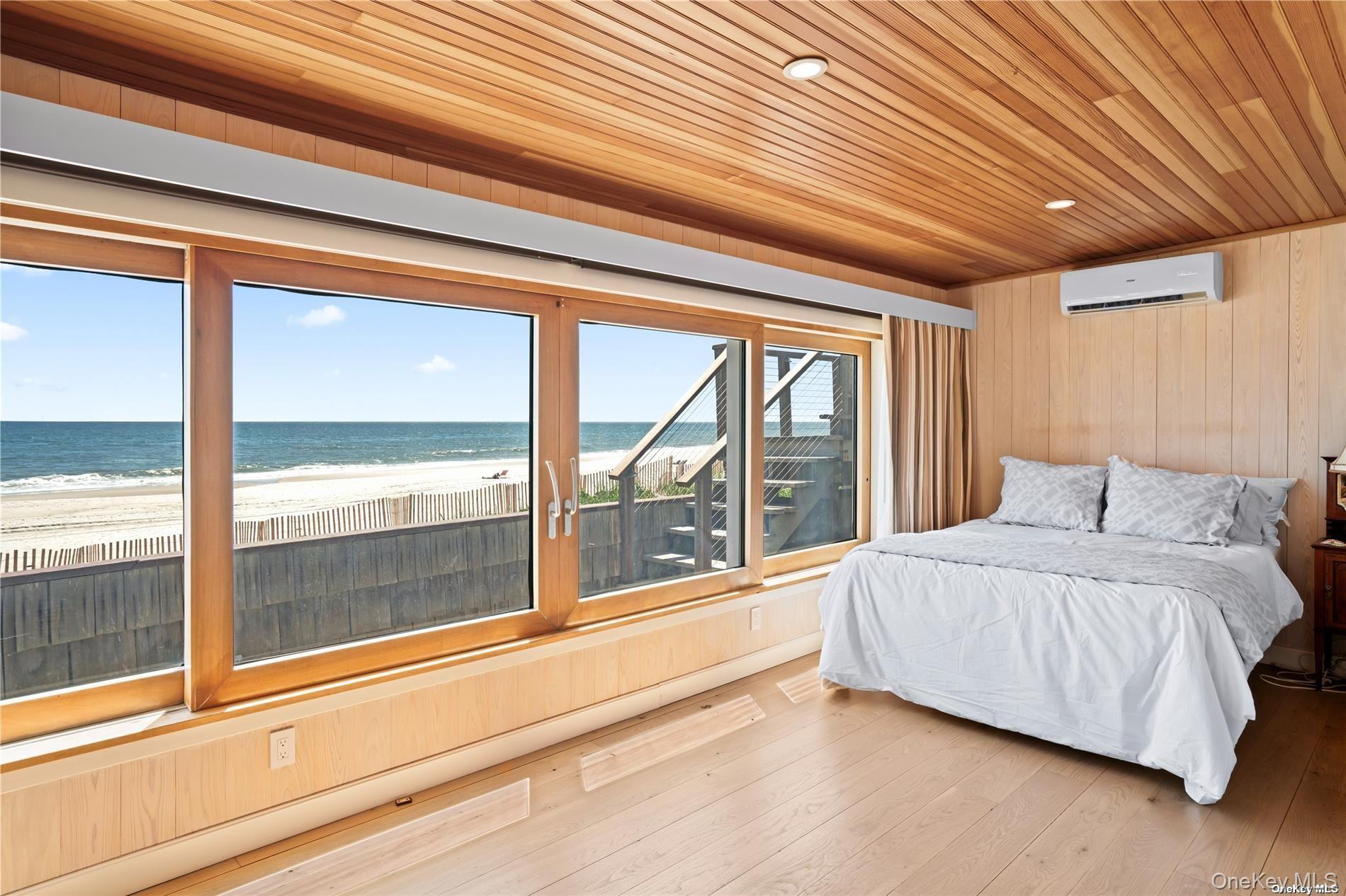 174 Dune Road Quogue, NY 11959 - Photo 22 of 35 a spacious bedroom with a large bed and a large window
