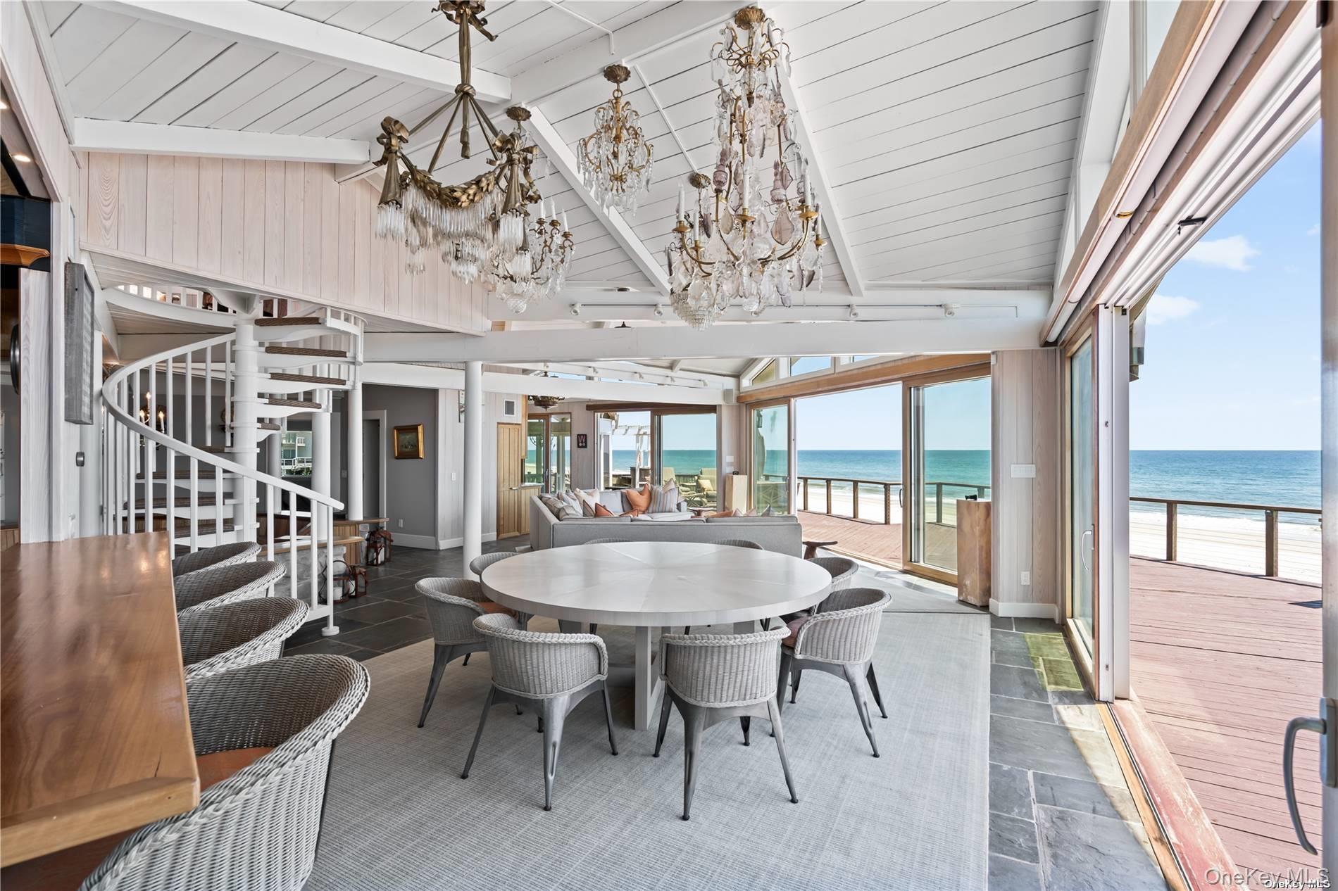 174 Dune Road Quogue, NY 11959 - Photo 9 of 35 a dining room with wooden floor a chandelier a wooden table and chairs