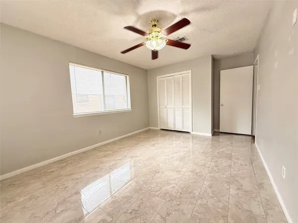 an empty room with windows and ceiling fan