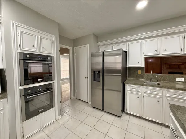a kitchen with granite countertop a refrigerator stove and sink