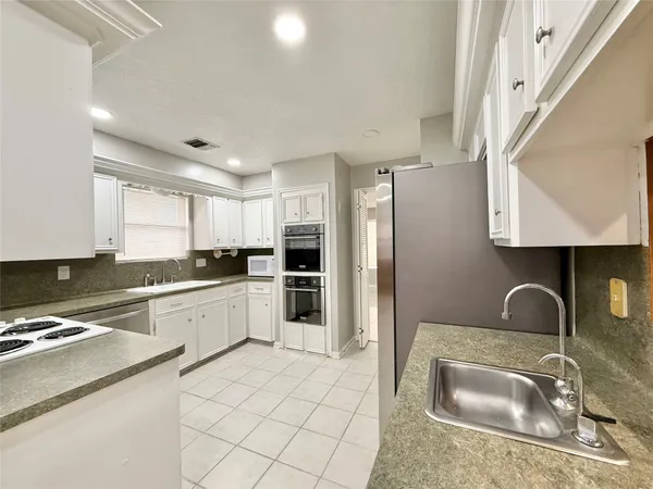 a kitchen with stainless steel appliances granite countertop a sink refrigerator and cabinets