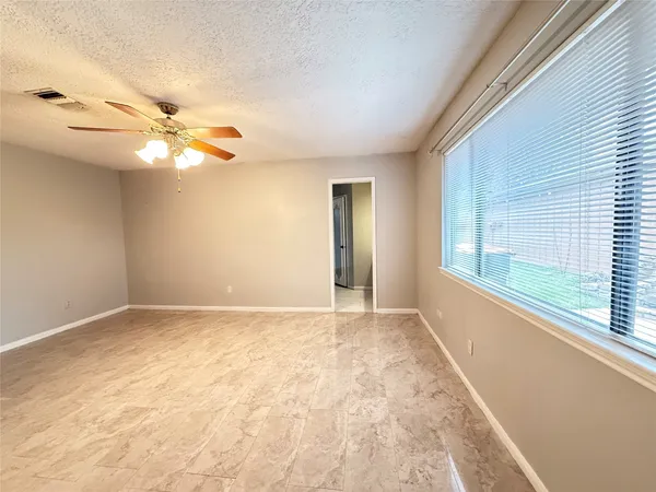 a view of an empty room with chandelier fan and fire place