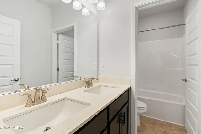 a bathroom with a tub sink double vanity and a mirror