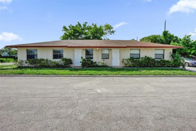 a front view of a house with a yard and potted plants