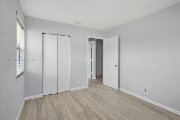 a view of an empty room with wooden floor and closet area
