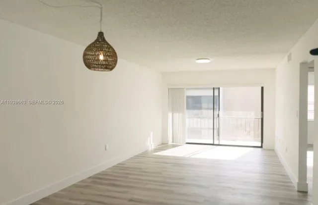 an empty room with wooden floor and natural light