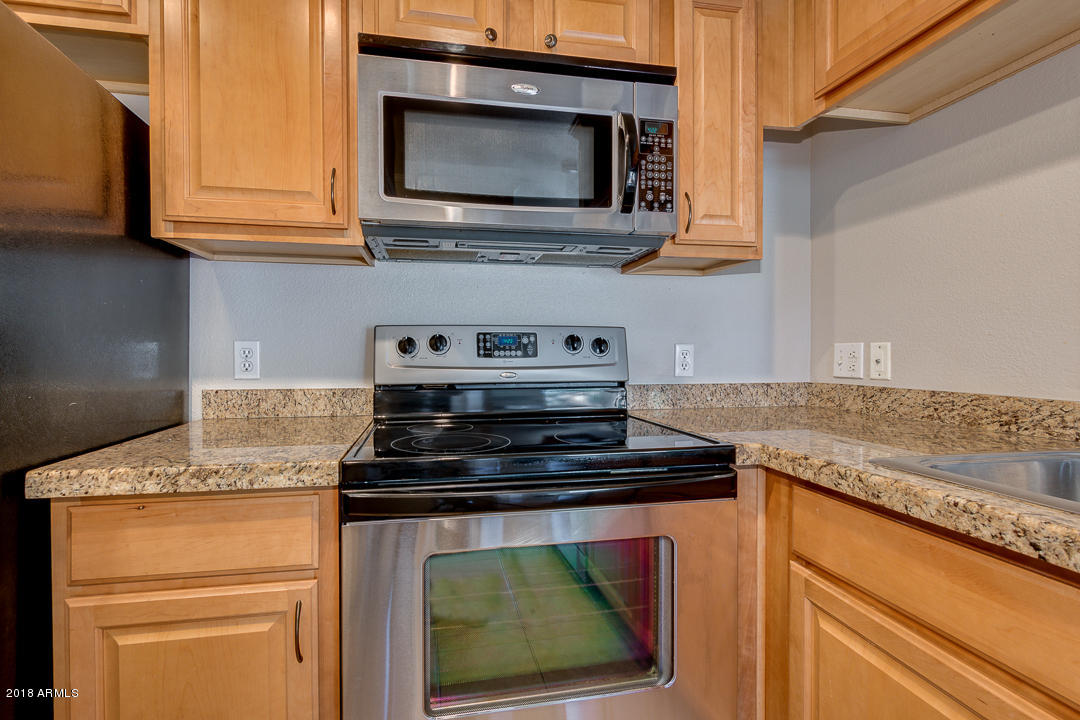 16013 South Desert Foothills Parkway, Unit 2090 Phoenix, AZ 85048 - Photo 17 of 43 a kitchen with stainless steel appliances granite countertop a stove microwave and cabinets