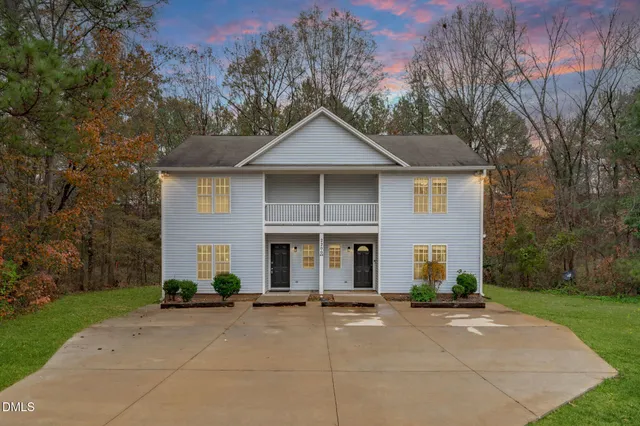a view of a brick house with a yard and large trees