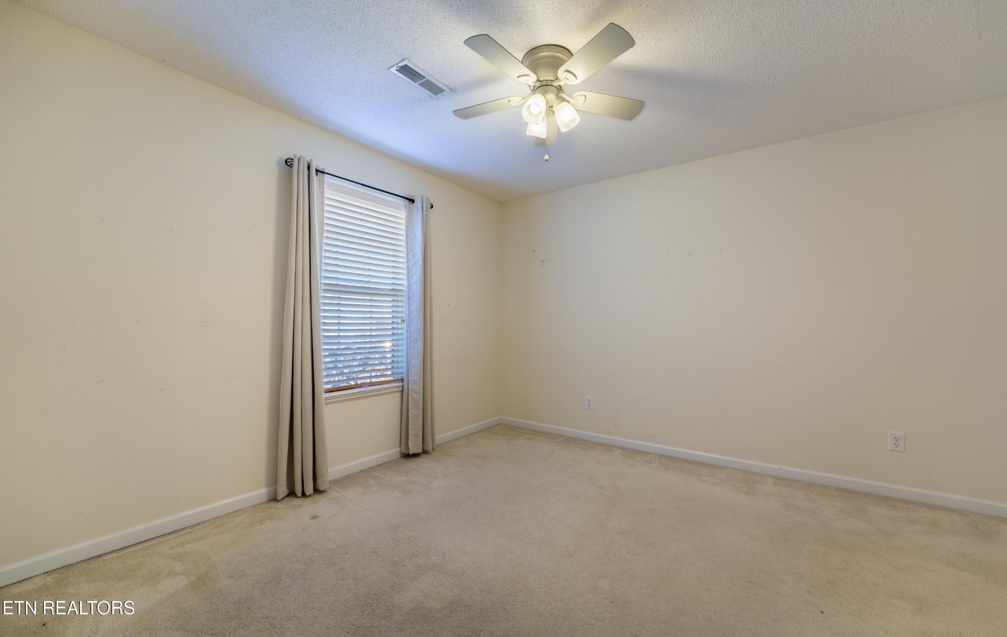 8024 Stablegate Way Powell, TN 37849 - Photo 19 of 35 an empty room with a chandelier fan and windows
