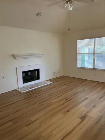 an empty room with wooden floor fireplace and windows