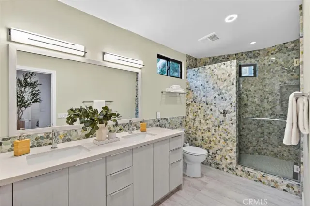 a bathroom with a granite countertop sink a toilet and shower