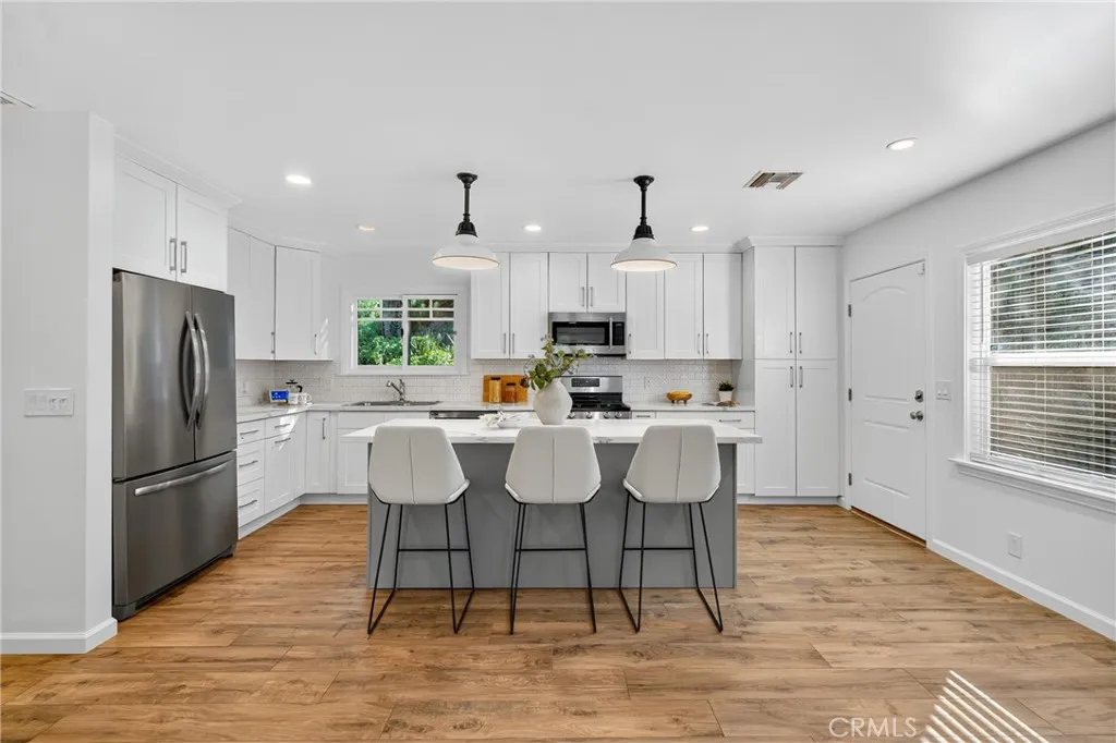 7572 McGroarty Terrace Los Angeles, CA 91042 - Photo 33 of 47 a kitchen with stainless steel appliances granite countertop a dining table chairs refrigerator and microwave