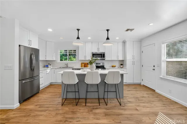 a kitchen with stainless steel appliances granite countertop a dining table chairs refrigerator and microwave