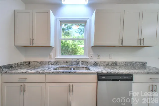 a kitchen with stainless steel appliances granite countertop a sink stove and white cabinets