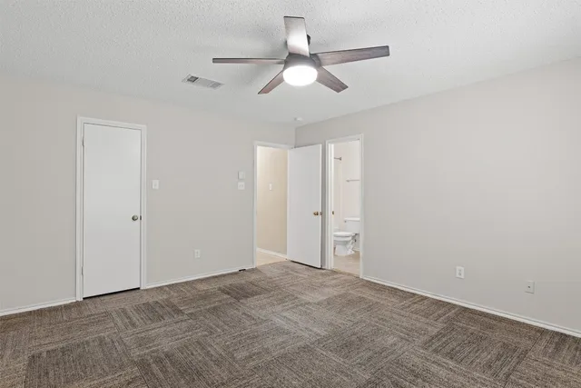 a view of an empty room and chandelier fan