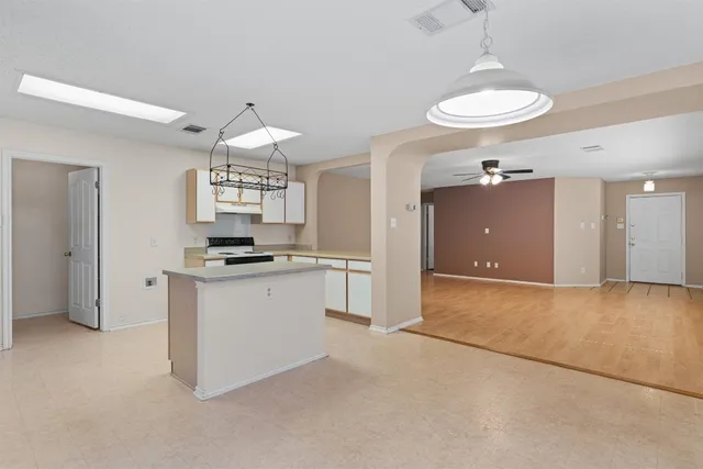 a kitchen with kitchen island granite countertop a stove a sink and a chandelier