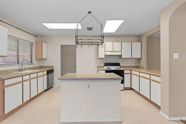 a large kitchen with stainless steel appliances granite countertop a stove a sink and a refrigerator