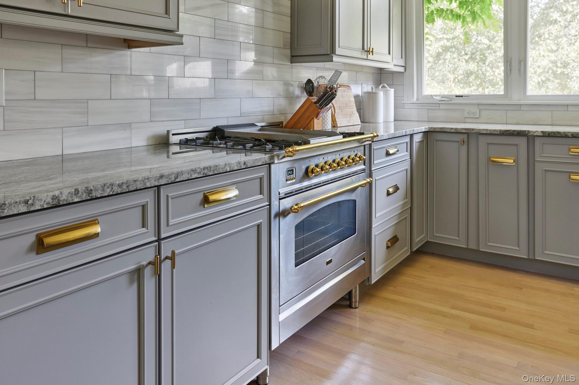 78 Schultz Hill Road Staatsburg, NY 12580 - Photo 18 of 50 Kitchen featuring stainless steel stove, gray cabinetry, backsplash, light wood-type flooring, and light stone counters