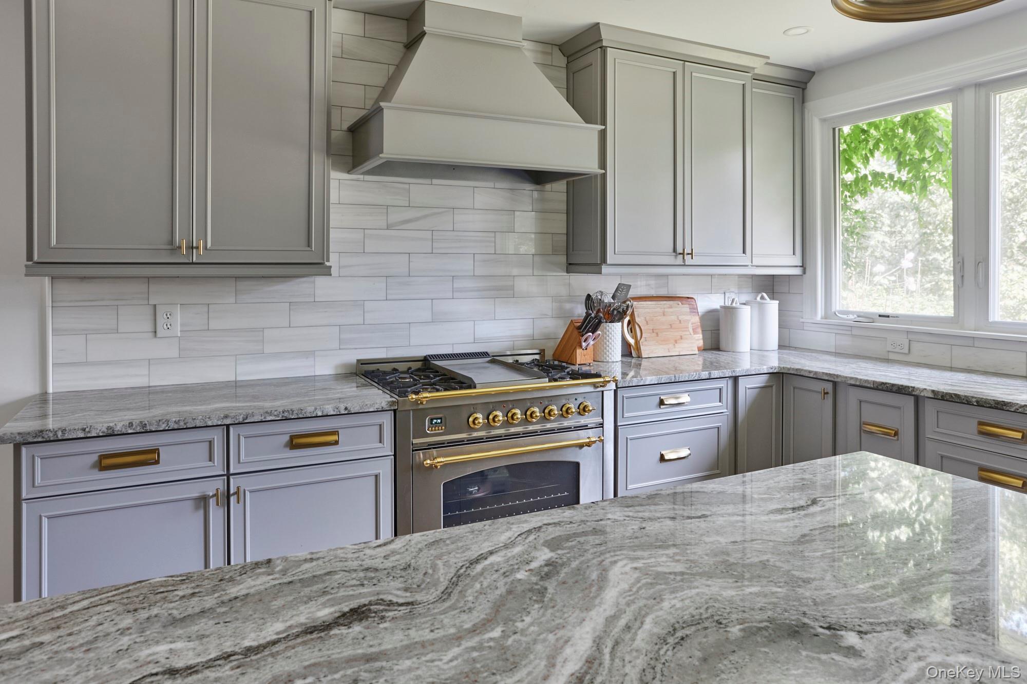 78 Schultz Hill Road Staatsburg, NY 12580 - Photo 19 of 50 Kitchen featuring stainless steel stove, custom range hood, gray cabinetry, tasteful backsplash, and light stone counters