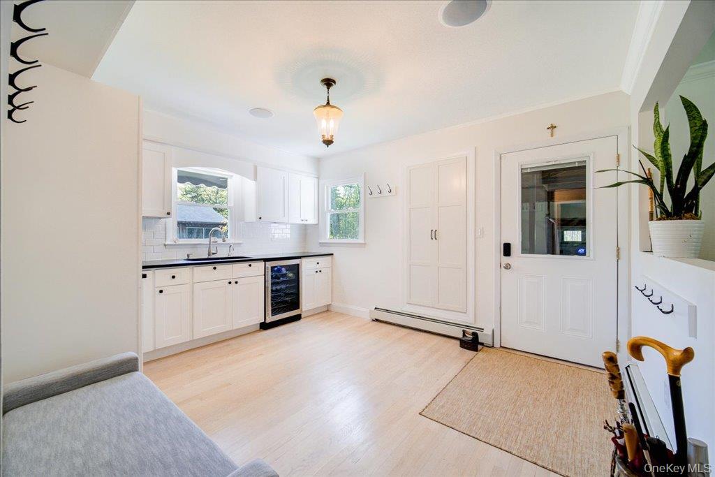 78 Schultz Hill Road Staatsburg, NY 12580 - Photo 44 of 50 Mudroom featuring beverage cooler, a sink, a baseboard heating unit, light wood-type flooring, and white cabinets