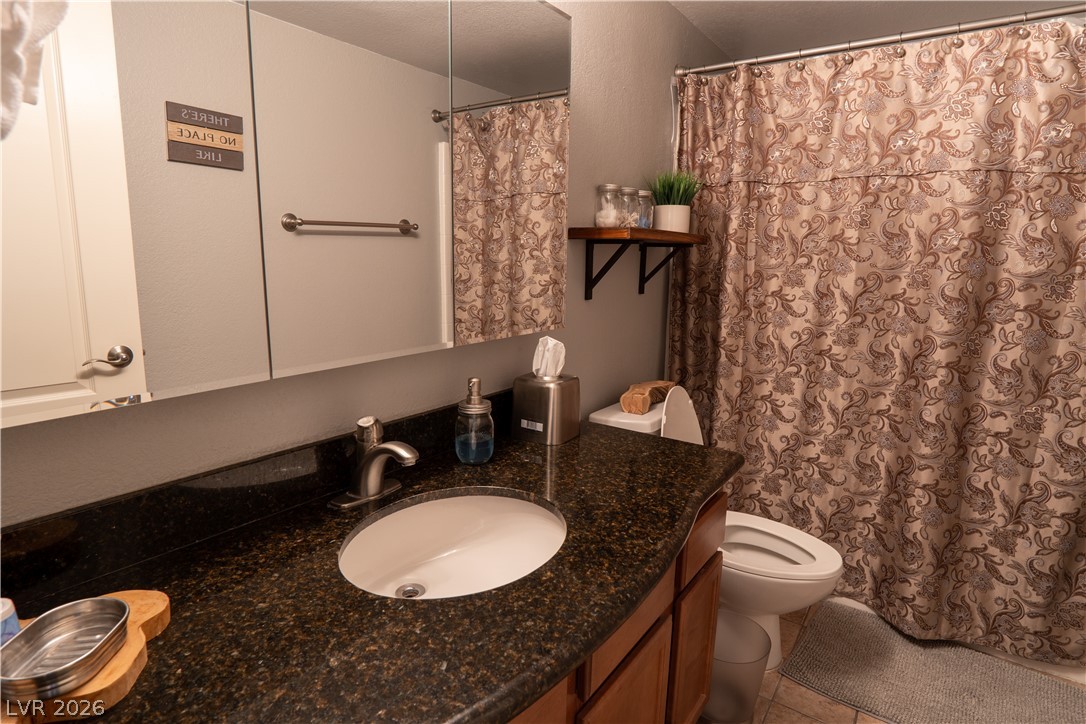 9325 West Desert Inn Road, Unit 264 Las Vegas, NV 89117 - Photo 6 of 10 Polished stone countertops pair with classic wood cabinetry in a functional bathroom layout.