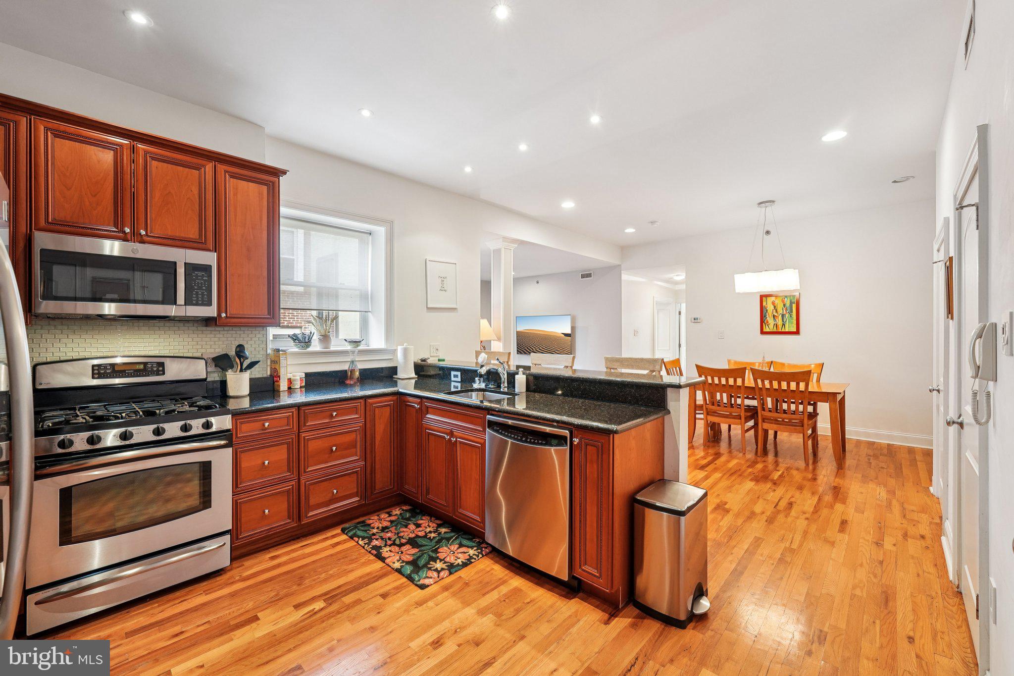 920 Clinton Street, Unit 3R Philadelphia, PA 19107 - Photo 4 of 24 a kitchen with stainless steel appliances granite countertop a stove top oven a sink dishwasher and a microwave oven with wooden floor