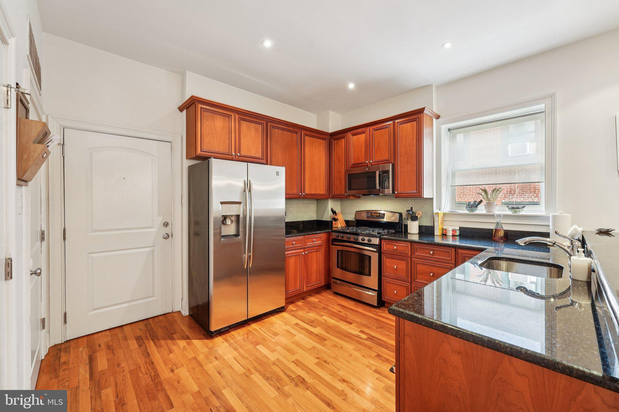 920 Clinton Street, Unit 3R Philadelphia, PA 19107 - Photo 5 of 24 a kitchen with stainless steel appliances granite countertop a refrigerator a sink dishwasher a stove and a refrigerator with wooden floor
