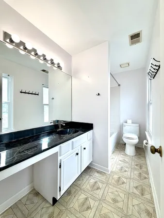 a spacious bathroom with a granite countertop sink a toilet and a large mirror