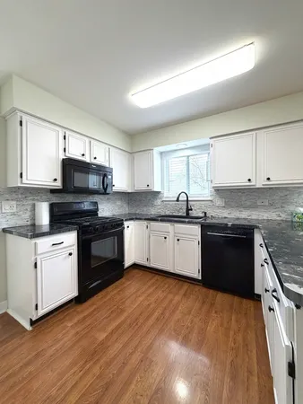 a white kitchen with granite countertop stainless steel appliances