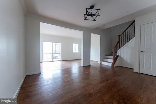 a view of an empty room with wooden floor and stairs