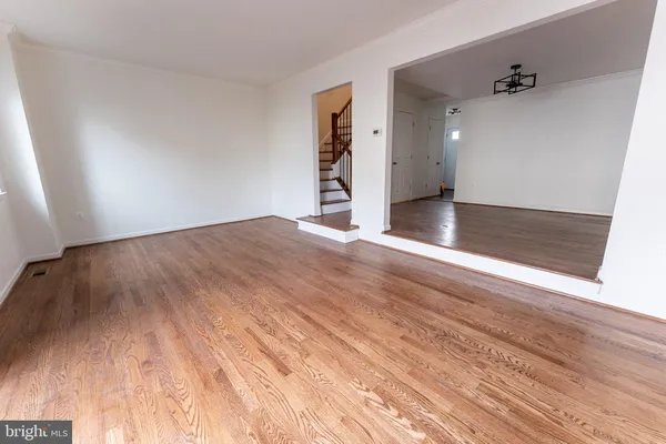 a view of an empty room with wooden floor and stairs