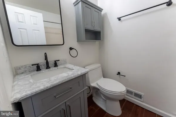 a bathroom with a granite countertop toilet sink and mirror