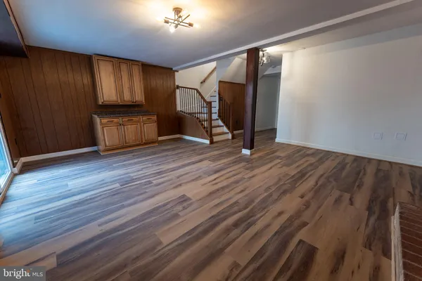 a view of an empty room with wooden floor and stairs