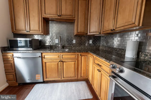 a kitchen with granite countertop wooden cabinets stainless steel appliances and a sink