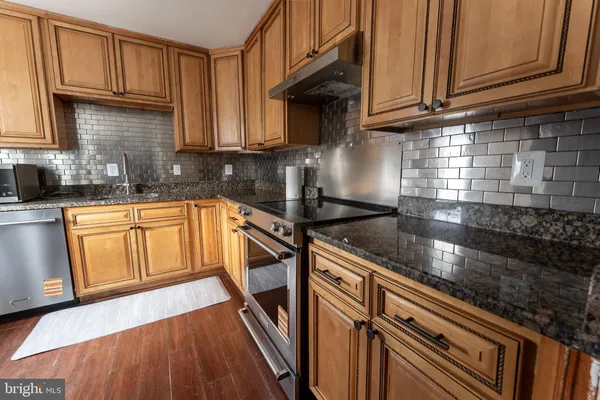 a kitchen with granite countertop a sink a stove and cabinets