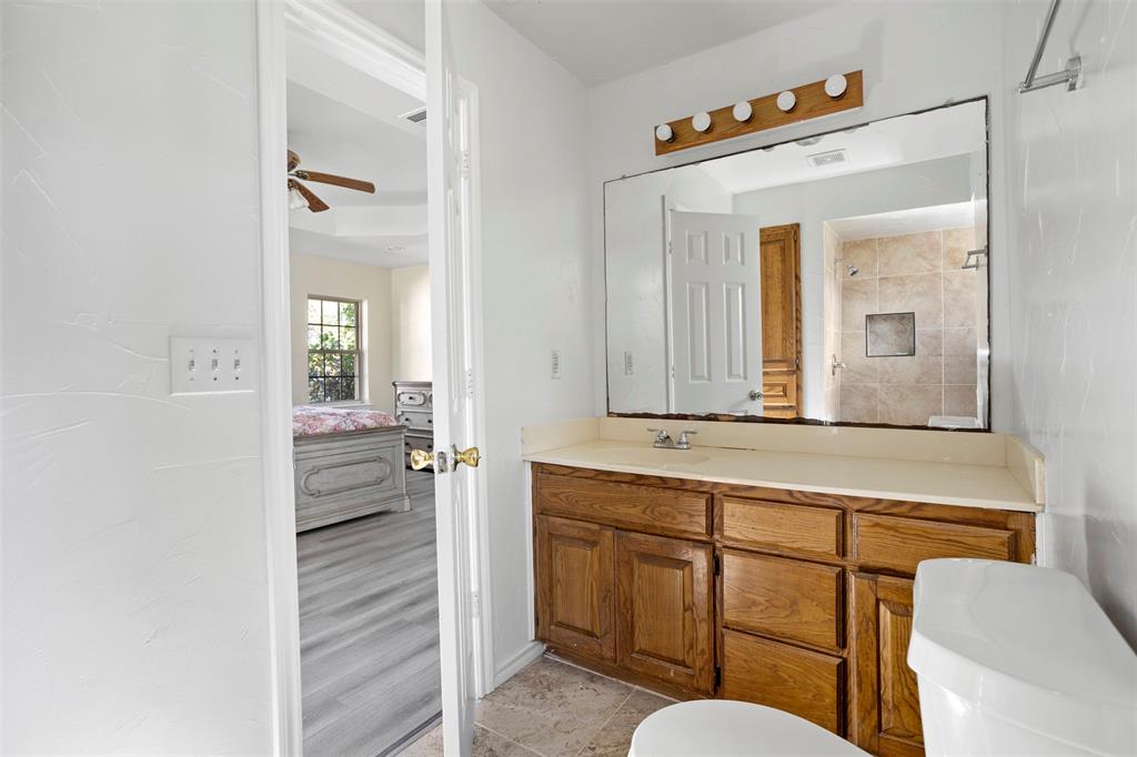 203 Main Street Red Oak, TX 75154 - Photo 23 of 32 a bathroom with a sink a mirror a toilet and a shower