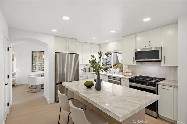 a kitchen with a refrigerator a stove a sink dishwasher a oven with white cabinets and wooden floor