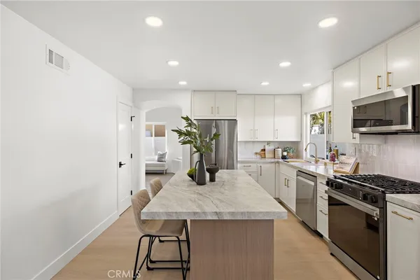 a kitchen with stainless steel appliances granite countertop a sink a stove a refrigerator a microwave with a dining table and chairs