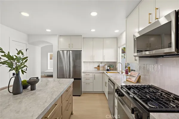 a kitchen with stainless steel appliances granite countertop a sink a stove a microwave a refrigerator a stove with wooden cabinets