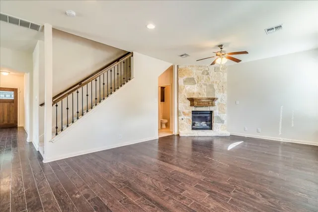 a view of an empty room with wooden floor and a ceiling fan