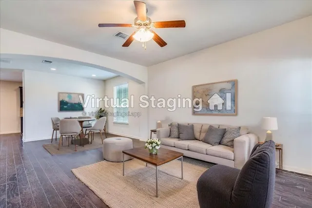 a living room with furniture wooden floor and a ceiling fan