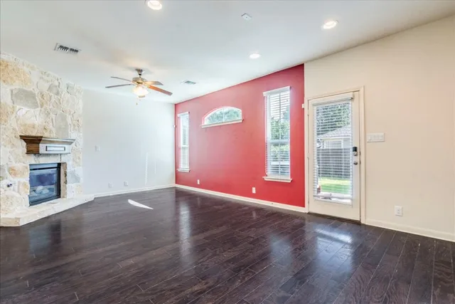an empty room with wooden floor fireplace and window